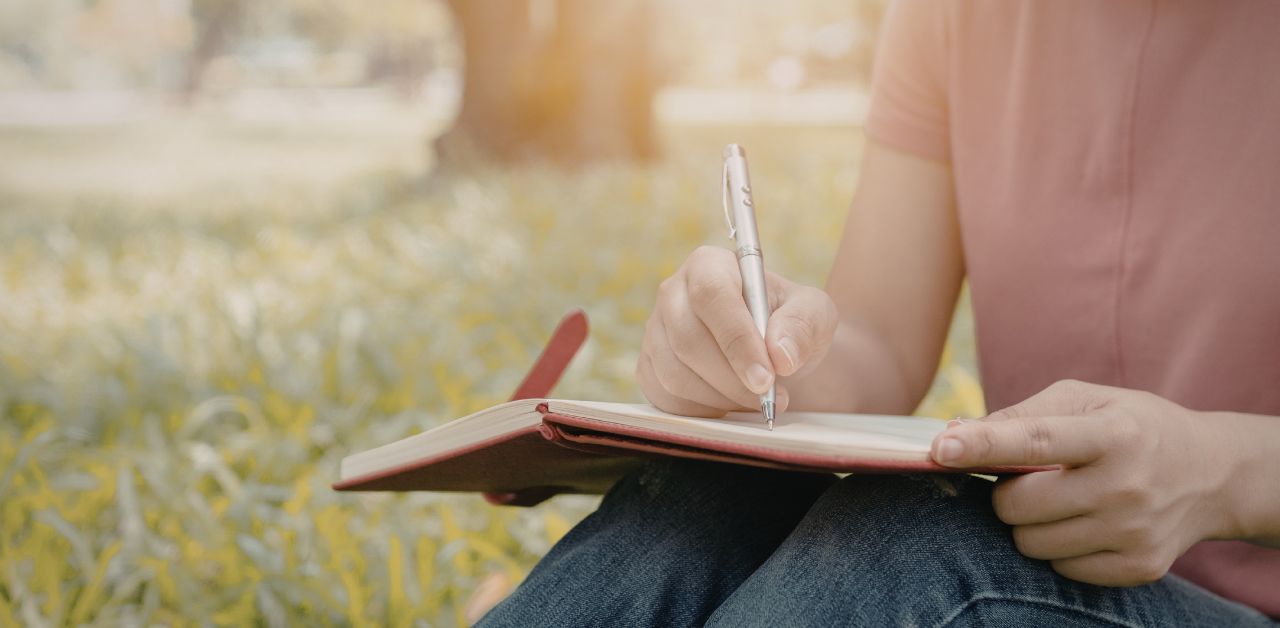 Person sitting quietly with a journal, reflecting and writing about life experiences and meaning