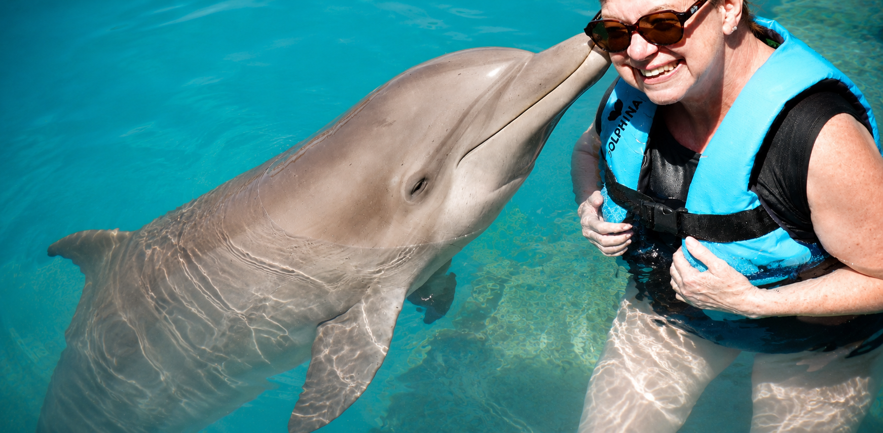 Woman sharing a joyful moment with a dolphin in clear turquoise water during a life-changing experience